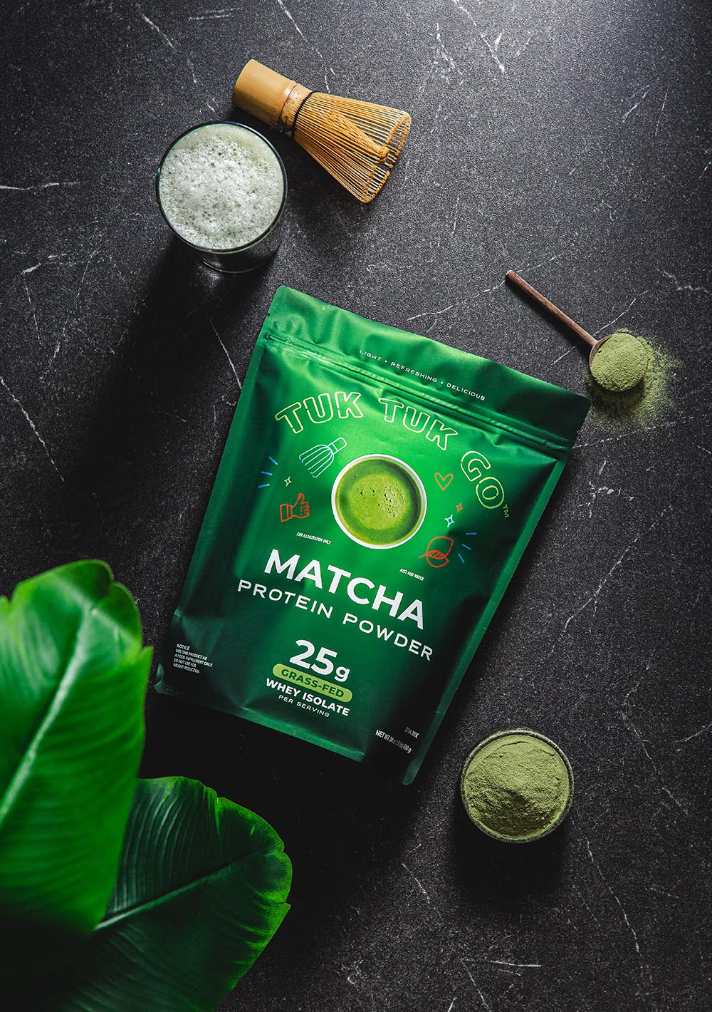 Matcha protein powder pouch top down shot with glass of matcha.