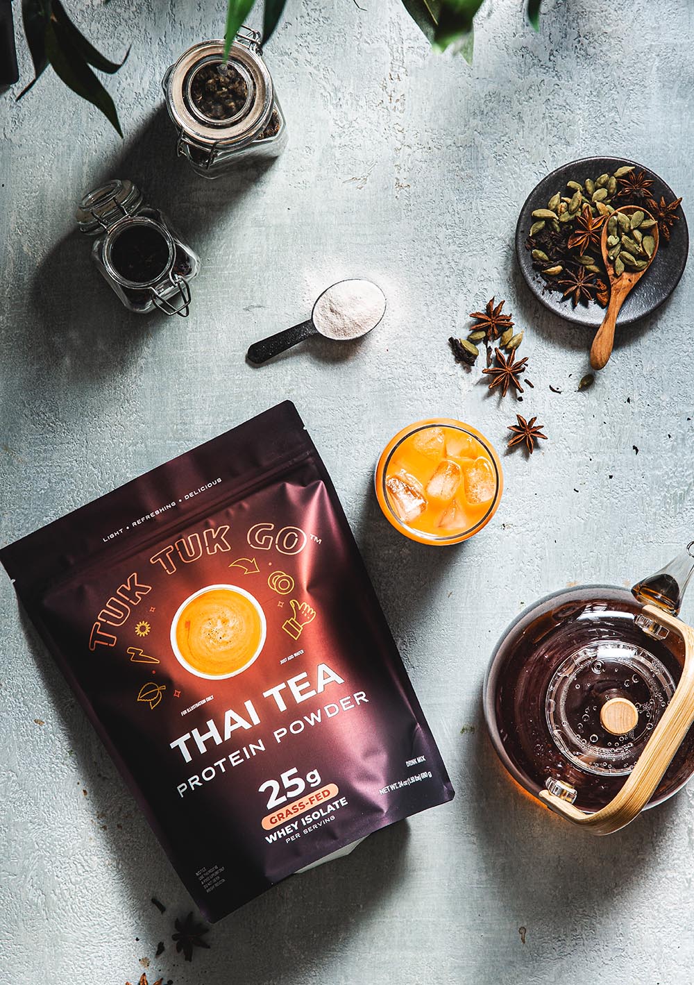 Thai Tea protein powder pouch top down shot with glass of thai tea.