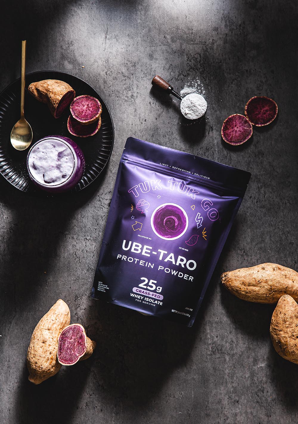Ube taro protein powder pouch top down with glass of drink and taro.